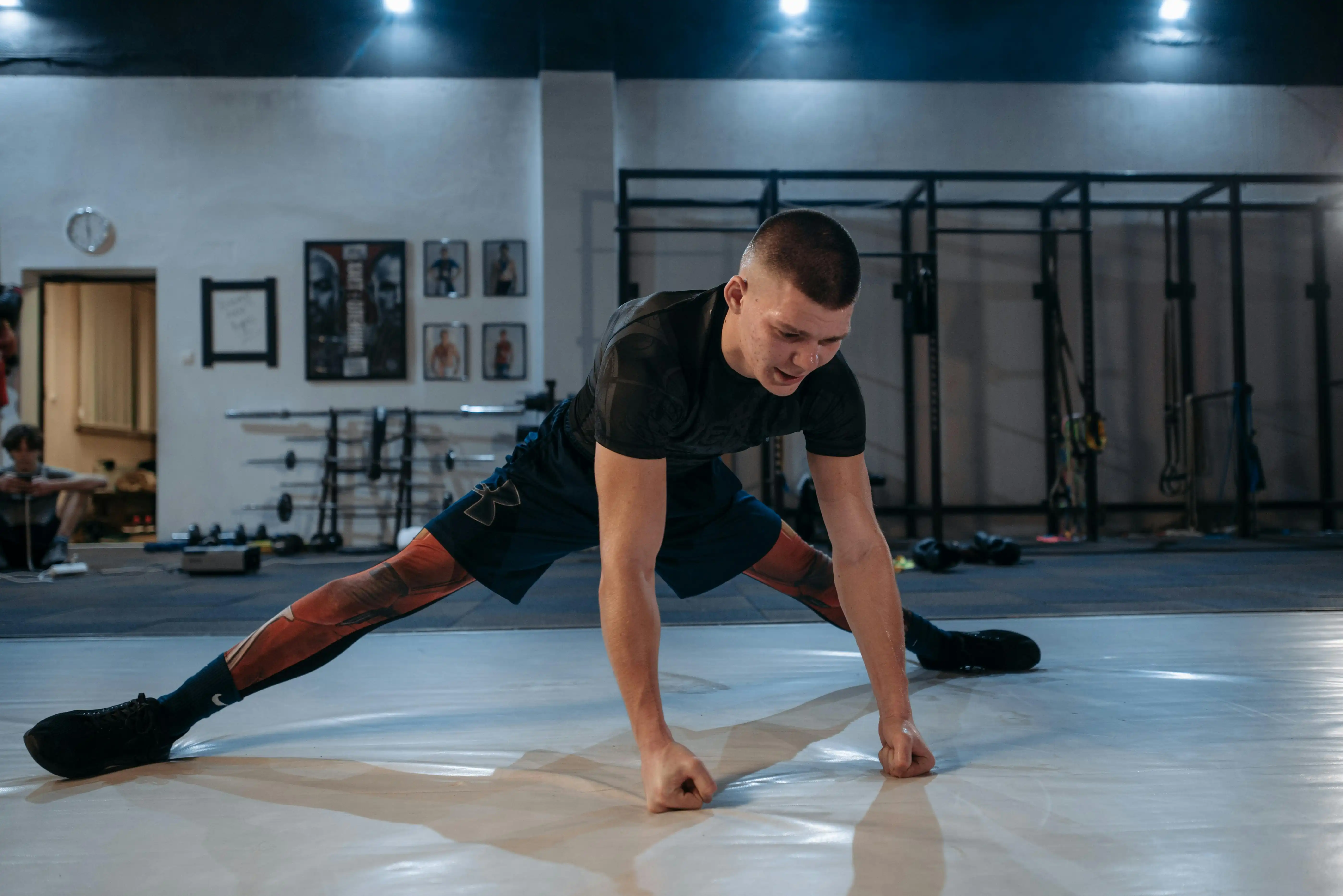 MMA fighter stretching on the gym floor during training, symbolizing recovery and flexibility supported by modern regenerative treatments like stem cell therapy.